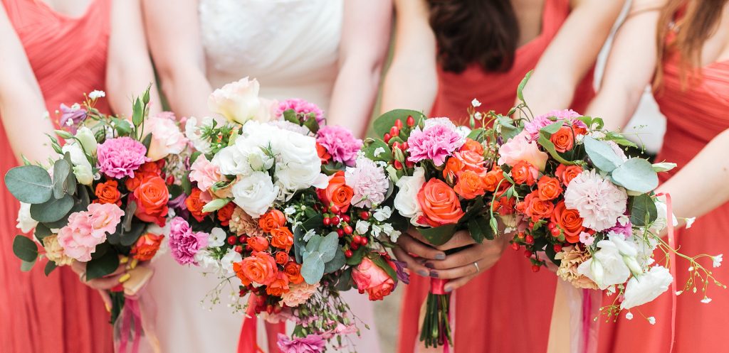 Bridesmaids and bride holds bouquets of flowers in hand.