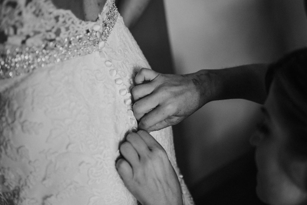 woman helping bride get dressed for wedding