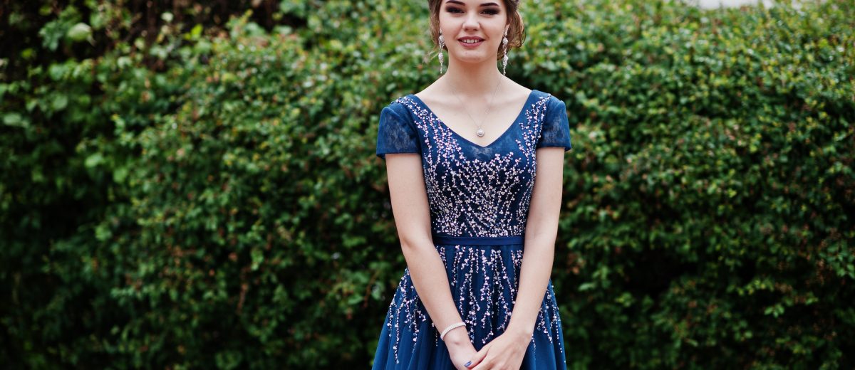 Portrait of a beautiful girl in elegant gown posing outdoors